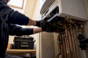 Technician hands servicing gas boiler internal parts