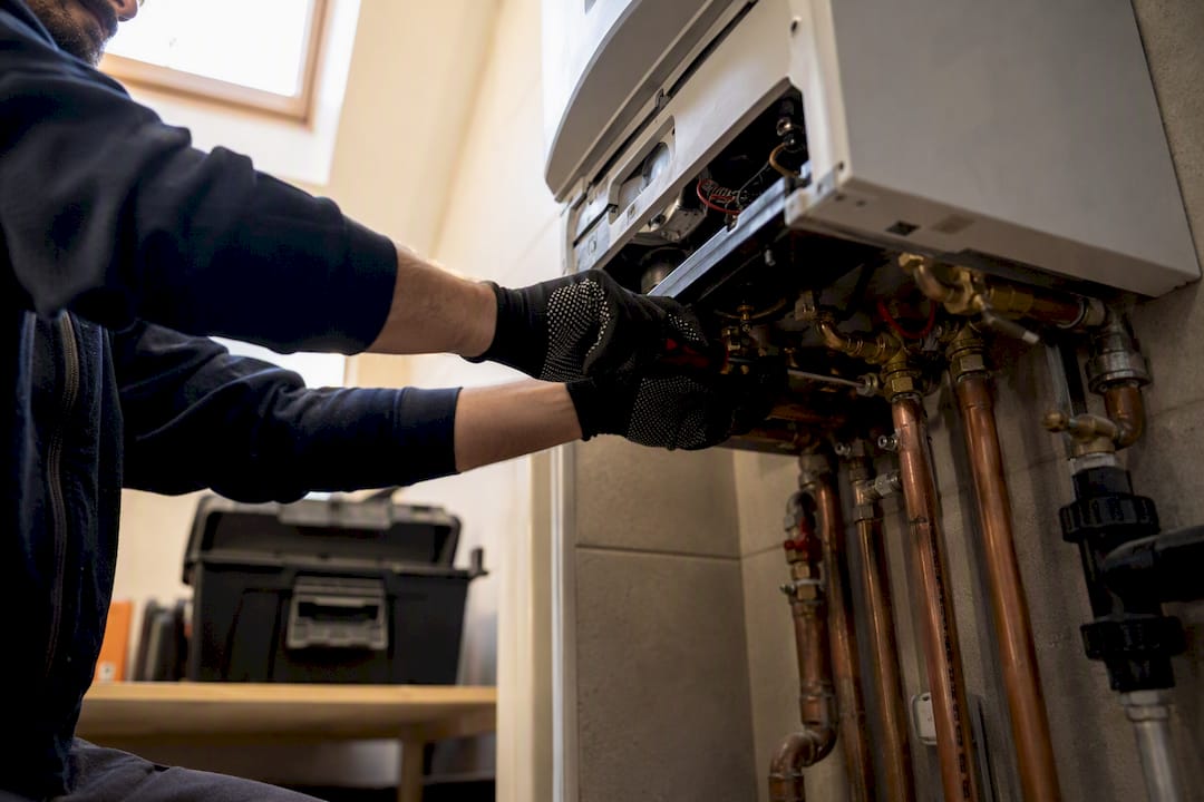 Technician hands servicing gas boiler internal parts