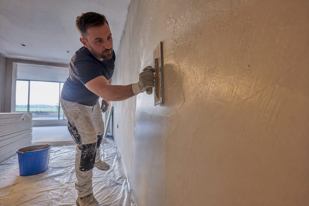 Plasterer applying skim coat to wall