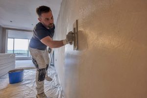 Plasterer applying skim coat to wall